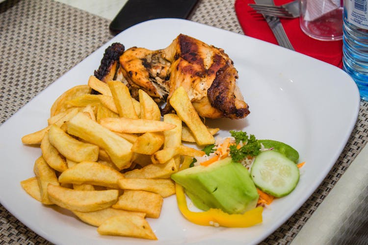 Grilled Chicken With French Fries And Cucumber On Plate