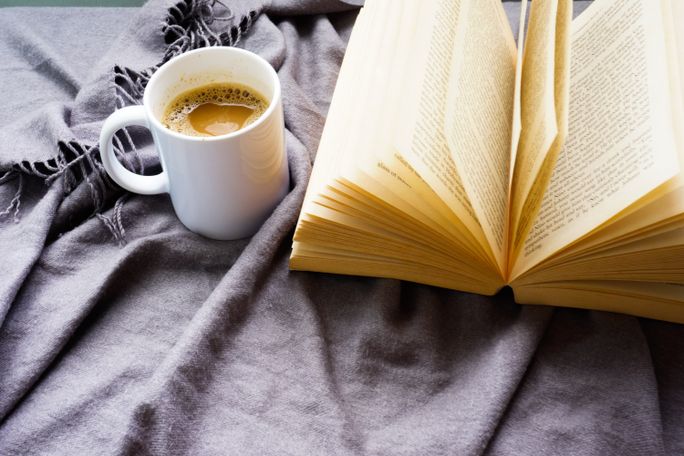 A mug of coffee and an open book on a soft grey blanket, photo by Leohoho on Pexels