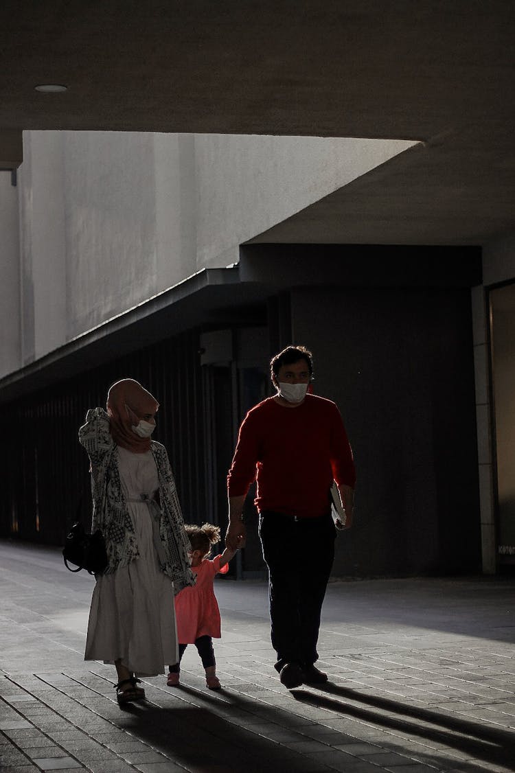 A Family Walking On The Street While Wearing Facemask