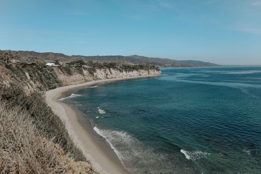 Beautiful panoramic view of rugged cliffs and serene sea under a clear blue sky.