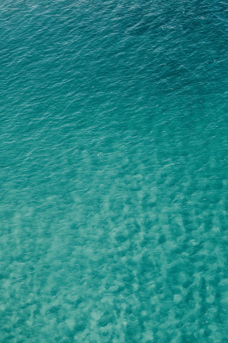 Captivating aerial view of teal ocean waters, showcasing serene textures and hues.