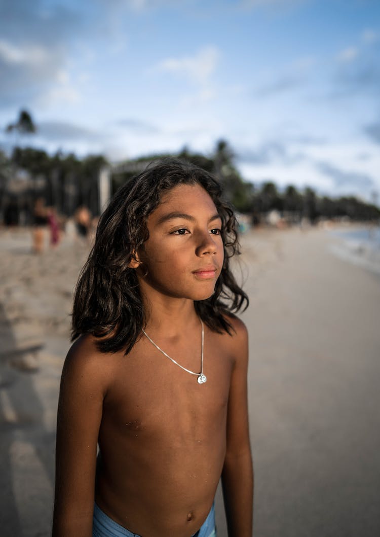 Calm Hispanic Boy Standing On Sandy Seashore