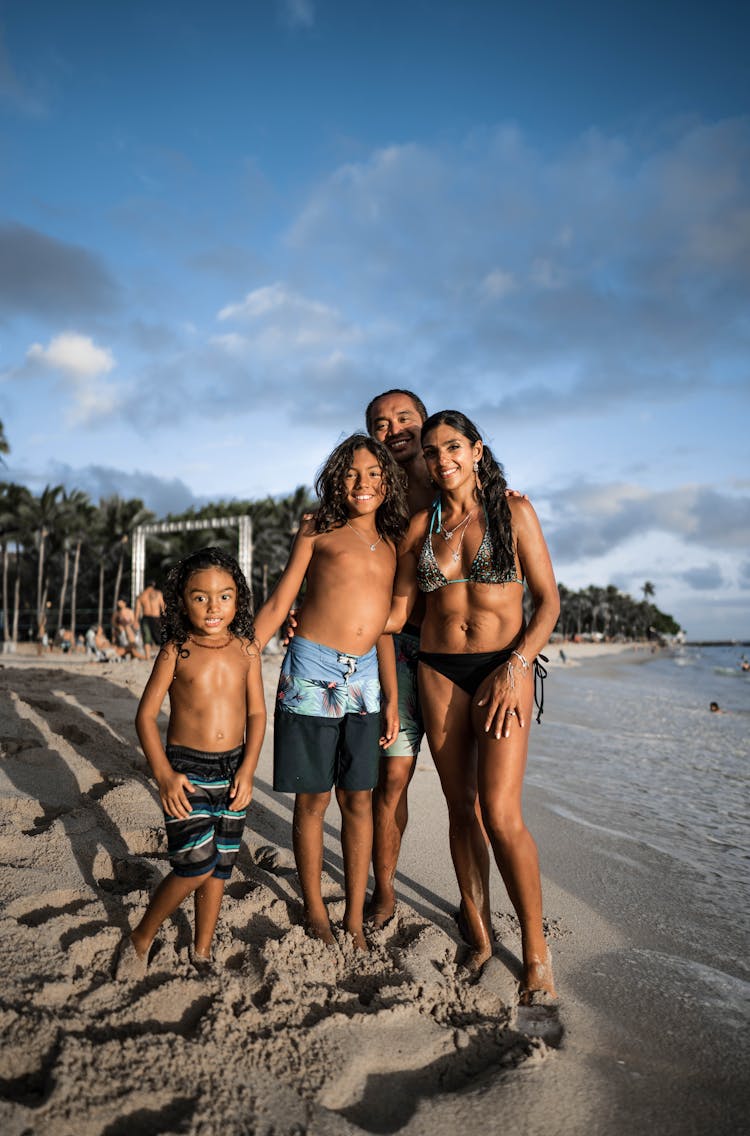 Joyful Hispanic Family Standing On Sandy Tropical Beach