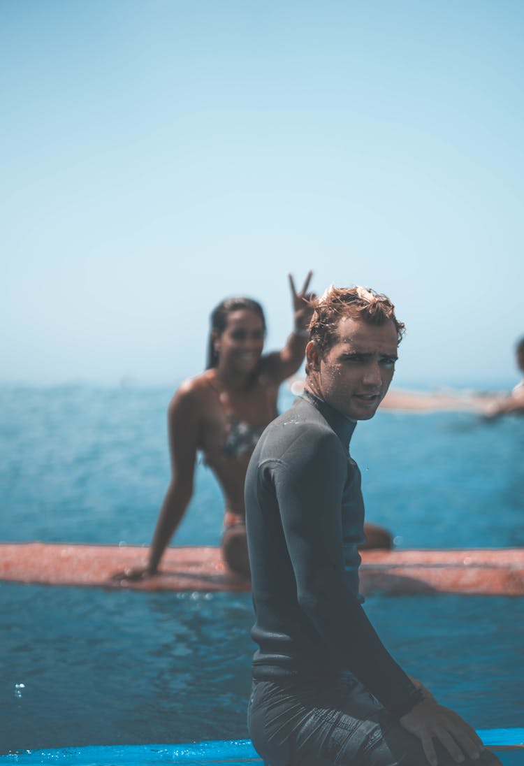 Surfers Resting On Board On Seawater