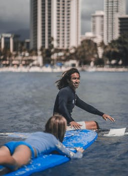 Two surfers enjoying the waves in an urban beachfront setting.