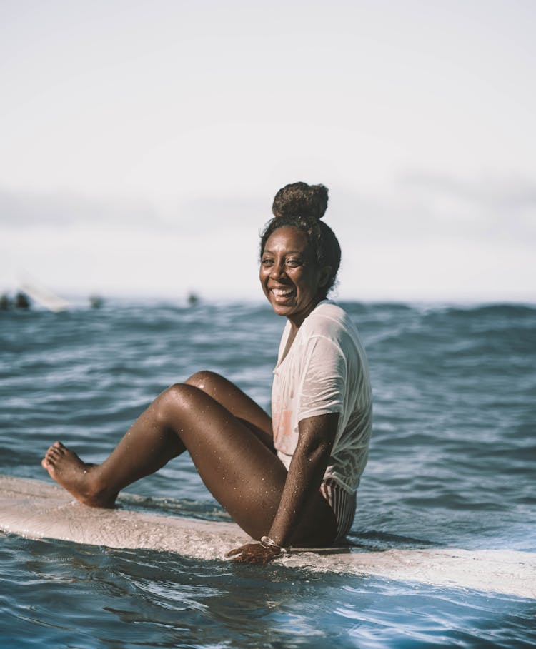 Cheerful Black Female Surfer On Surfboard On Sea