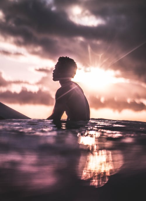 Nicht Erkennbarer Schwarzer Mann, Der Sich Bei Sonnenuntergang Im Meerwasser Entspannt
