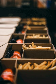 A row of cardboard boxes filled with crispy french fries and sauces.