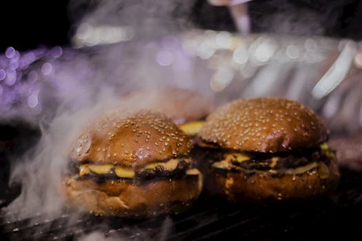 Close-up of delicious smoky burgers with cheese grilling, capturing the mouth-watering aroma.