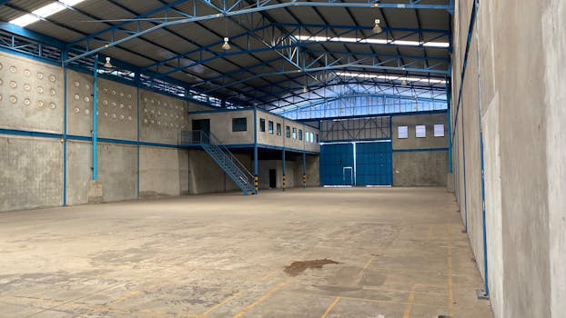 Empty warehouse with blue steel frame and concrete walls in Bangkok.