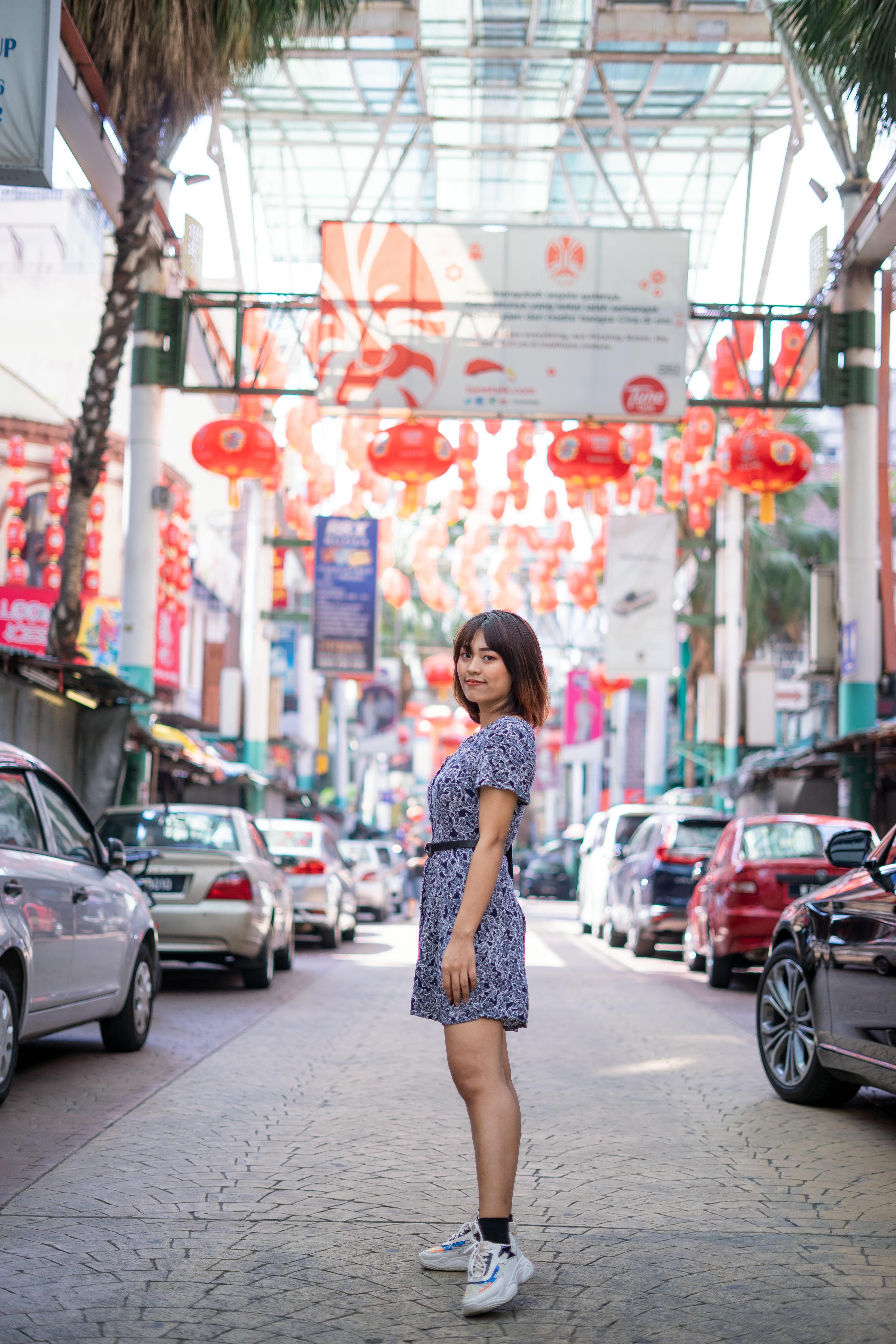 在马来西亚亚庇，一位亚洲妇女站在充满活力的街道装饰中