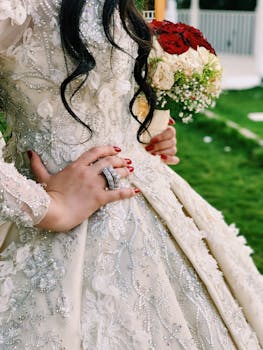 Detailed shot of a bride's hand on a decorated gown, holding a bouquet.