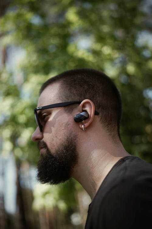 Close-up of a Man Wearing Sunglasses and Wireless Earphones