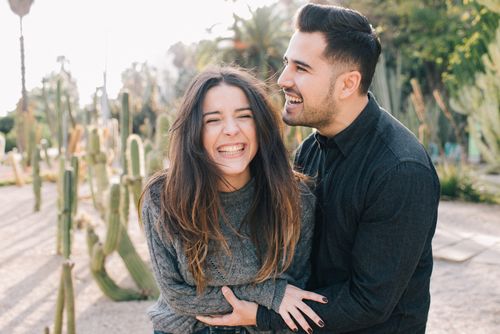 Free Happy couple sharing a joyful moment in a sunlit garden with cacti. Stock Photo