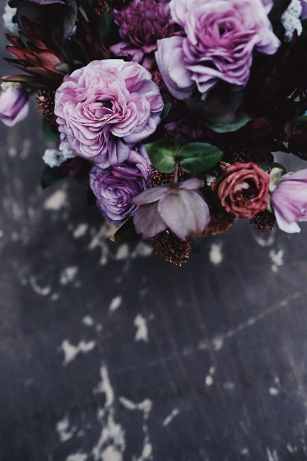 A beautiful bouquet of purple flowers captured from above, set against a rustic background.