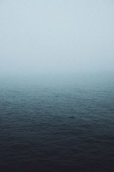 用宁静的蓝色调色板捕捉黎明时分薄雾笼罩的宁静海平线
