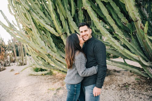 A Couple Standing Beside Big Cactus Plants 