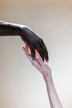 两只不同肤色的手相互触摸的特写照片，象征着团结和多样性