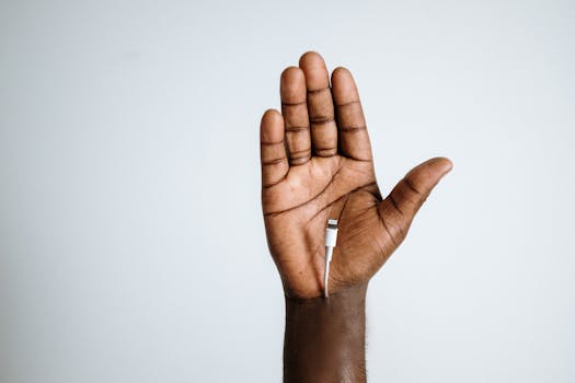 Close-up of a hand holding a charging cable with empty space, symbolizing technology in human life.