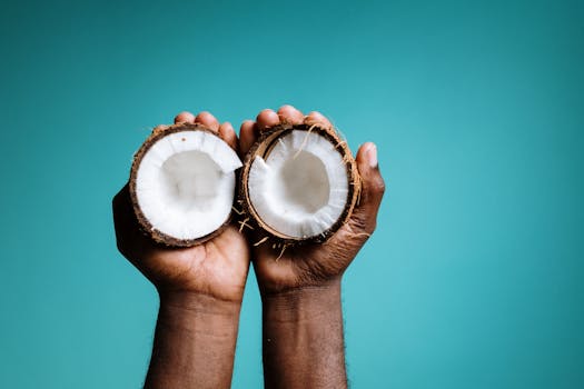 Vibrant blue background highlighting hands holding open coconut halves symbolizing tropical healthy eating.