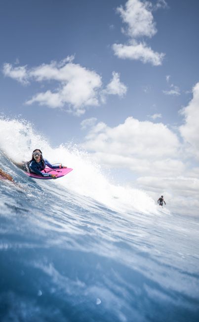 Capture the thrill of surfing with riders cutting through ocean waves under a bright summer sky.