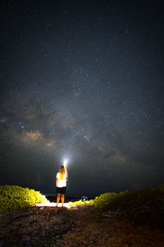夜空下，一个人站在宁静的户外，被星星和银河照亮