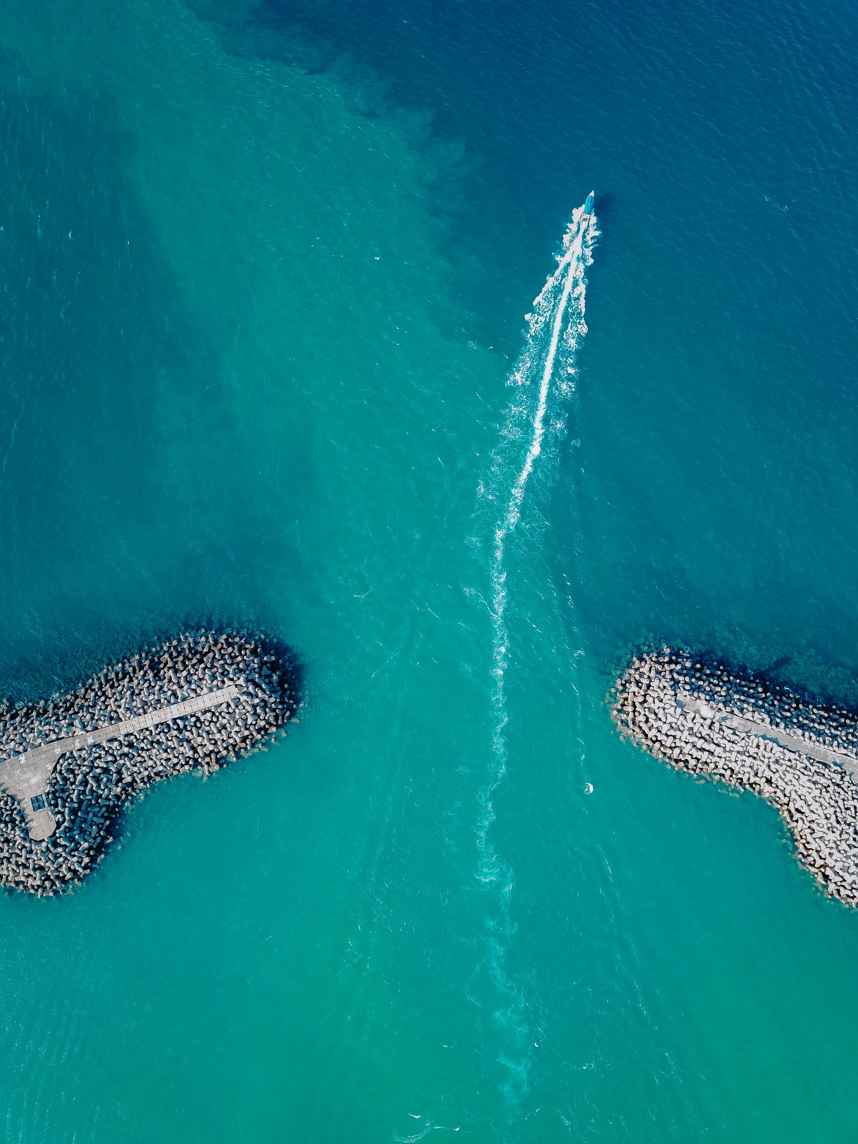 aerial view of a boat crossing between breakwaters