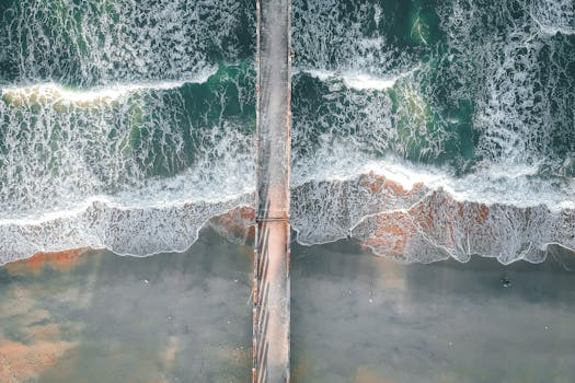 Stunning aerial view of a pier stretching into the vibrant ocean waves.