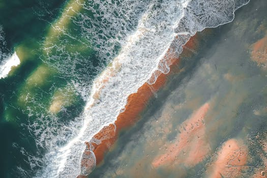 Discover the tranquility of ocean waves meeting sandy shores in this stunning aerial seascape photograph.