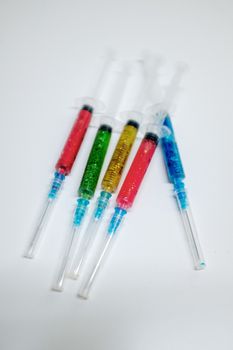 一张创意概念图像：白色表面上，注射器充满彩色闪光