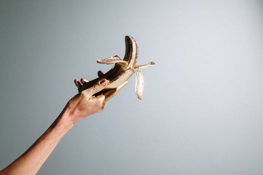 一张手绘的金色艺术照片中，一根金色香蕉被置于柔和的背景之上