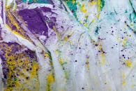 白色织物上，彩色粉末活力四射，构成动态抽象图像，展现艺术创造力