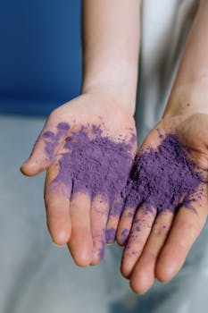 双手握着充满活力的紫色粉末，展现了创造力和色彩