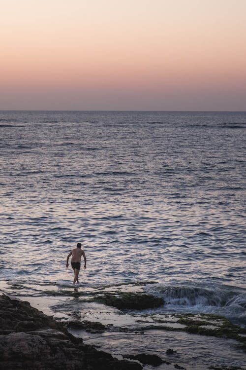 Man Standing on Seashore during Sunset