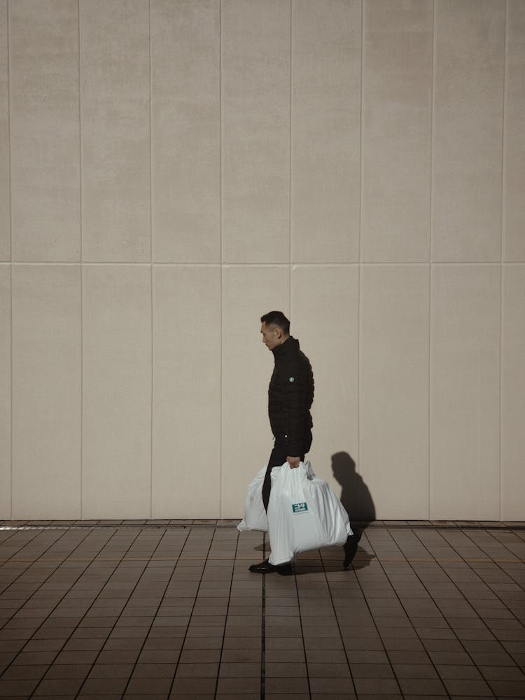 Man Walking On Sidewalk Carrying Shopping Bags