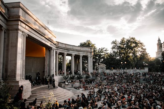 A large crowd gathers at the Greek Theatre in Denver during sunset for a public event.
