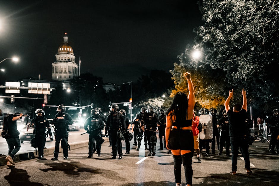 Protesters and police face off in Denver at night, capturing a moment of civil unrest.