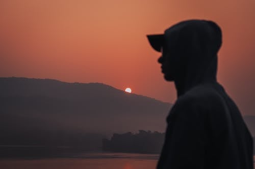 Silhouette of Man Wearing Hoodie While Looking Afar