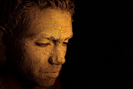 Profile of a man with a dried clay mask against a black background, capturing an artistic and dramatic mood.