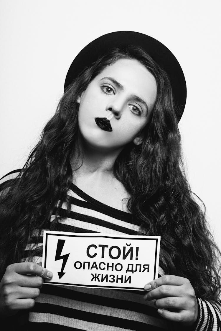 Woman In Black And White Stripe Shirt Holding A Danger Sign