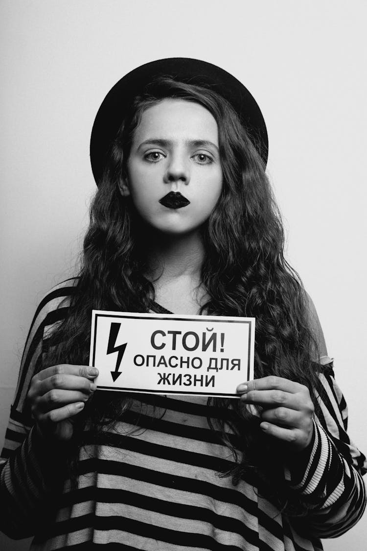 Unemotional Woman Looking At Camera While Holding A Danger Sign