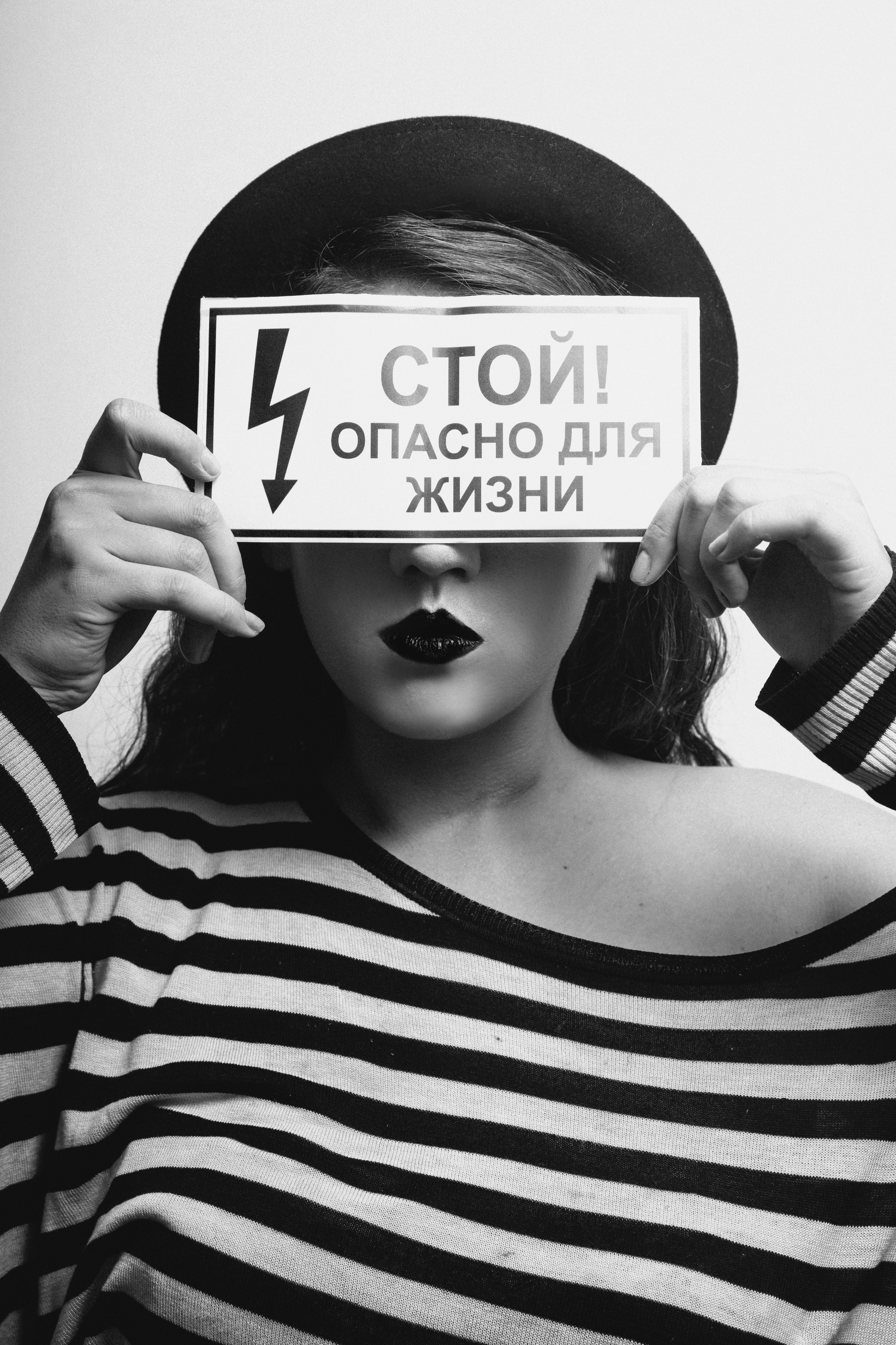 black and white photo of a woman holding a sign covering her eyes