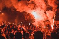 Crowd of unrecognizable activists with burning torches standing on street among smoke during demonstrations at night