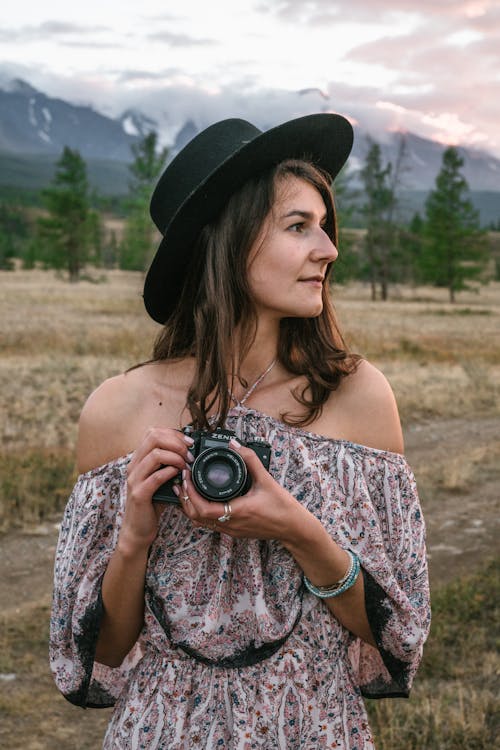 Woman holding a Camera on Grass Field