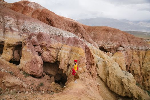 A woman stands amidst vibrant rocky terrain, showcasing adventure and natural beauty.
