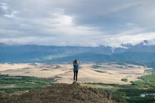Free Back View Footage of a Person Standing on Rock Formation While Looking at the Scenery Stock Photo
