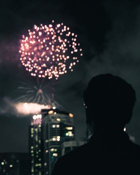 城市庆祝活动期间，夜空中绚烂的烟花映衬出天际线下一个人的轮廓