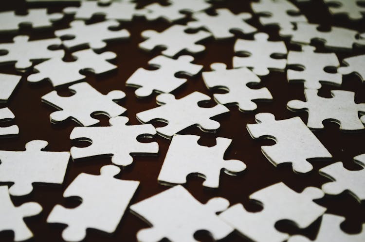 White Puzzle Pieces On A Brown Surface