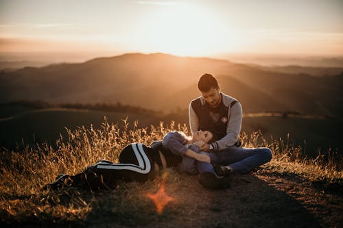 Sweet Couple Sitting on Ground while Looking at Each Other During Sunset