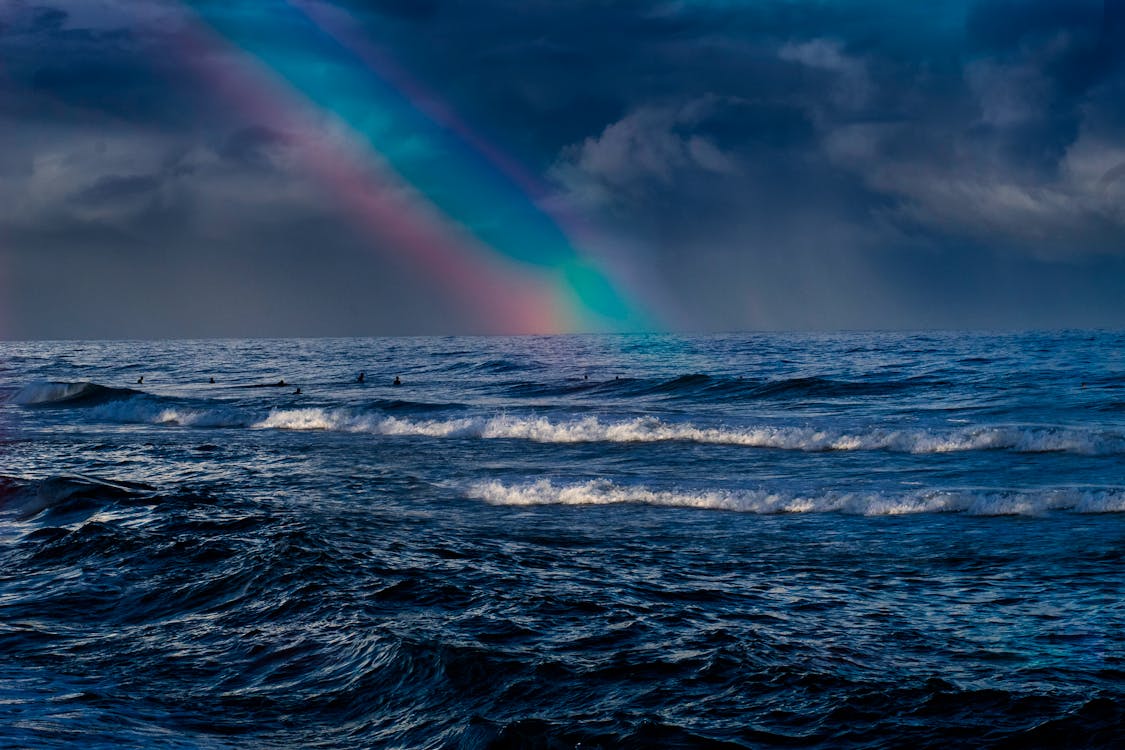 Big Sea Waves Under Rainbow and Cloudy Sky